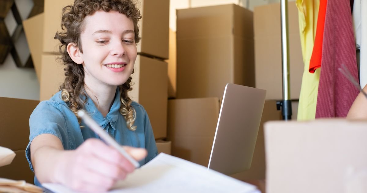 Small business owner working at a laptop surrounded by packages and paperwork