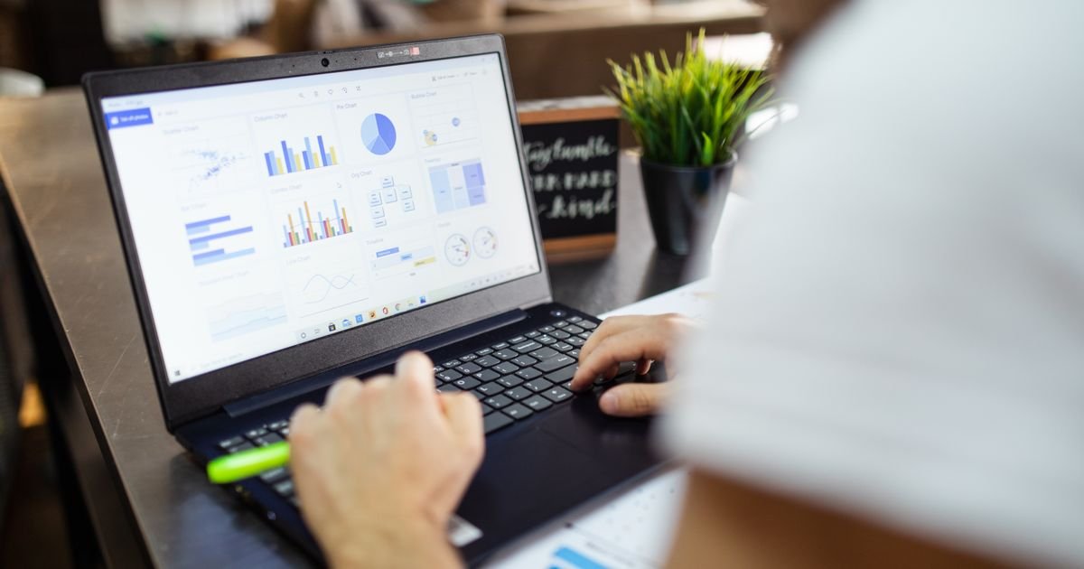 Analyst reviewing charts and figures on a laptop at an office desk