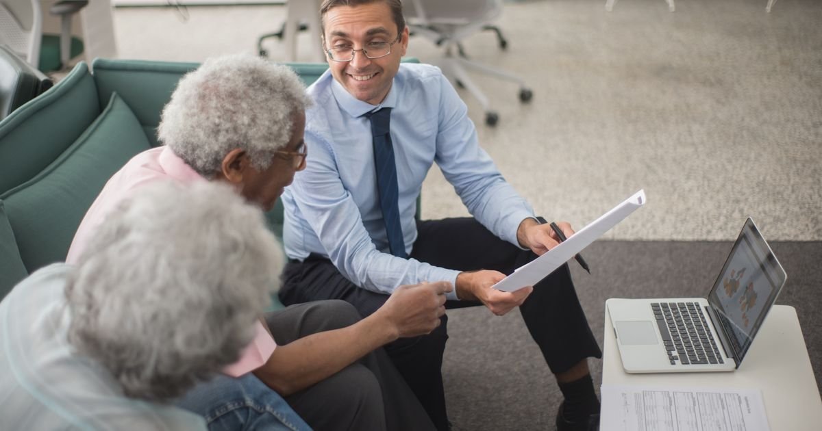 Insurance consultant reviewing documents with two clients in an office