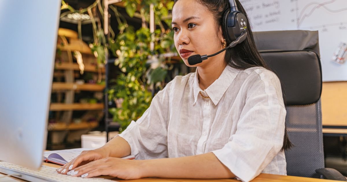 Professional working at a computer with a headset in a home office