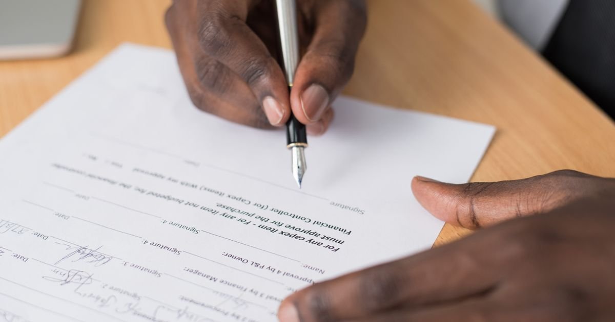 Close-up of hands signing a property contract on a desk
